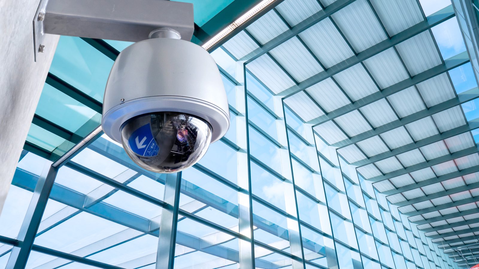 Security camera mounted beneath the glass atrium ceiling of a commercial building